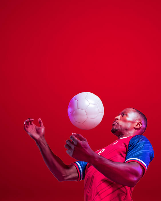 A footballer receiving the ball on his chest against a red background